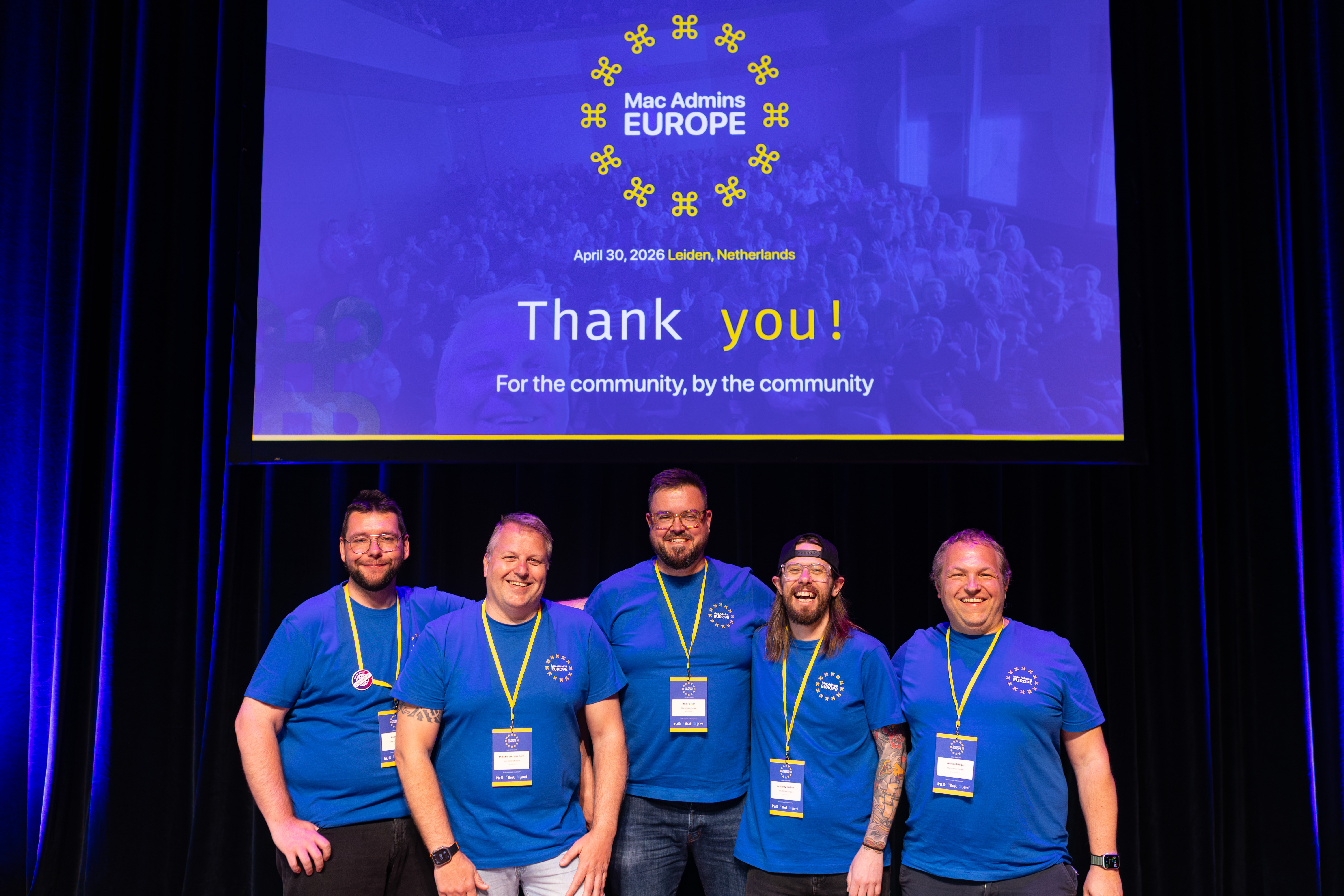 Mac Admins Europe organizers standing on stage beneath a thank-you screen at the 2026 event